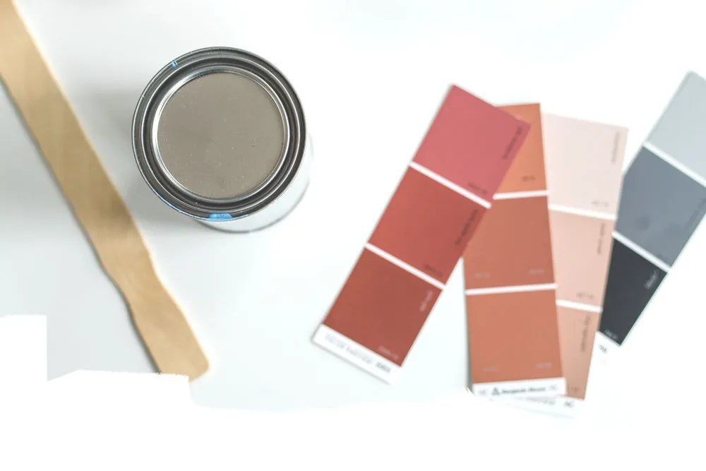 Nuancier de peinture avec pot ouvert Pot de peinture gris ouvert accompagné de nuanciers de couleurs chaudes et froides